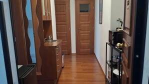 A hallway with wooden flooring, wooden doors, a kitchen area with cabinets and a sink, and a black shelf with kitchen items. - Metro Angel Apartment 2 - 4 guests (Prague)