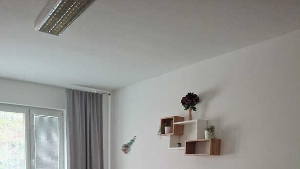 A hotel room with a large bed, a desk, a chair, a small table, and a window with curtains. - Metro Angel Apartment 2 - 4 guests (Prague)