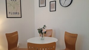 A room with a round table, two chairs, a clock, and framed pictures on the wall. - Metro Angel Apartment 2 - 4 guests (Prague)