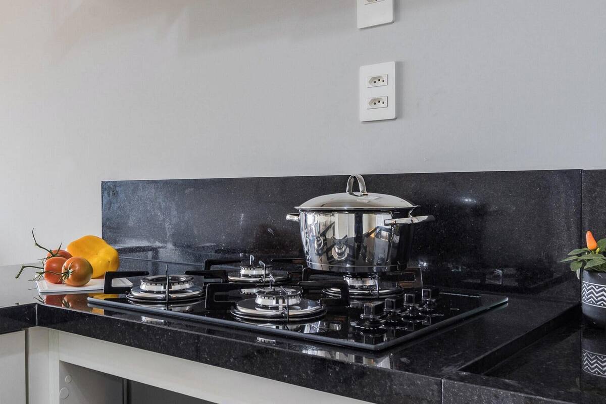 A modern kitchen with a black countertop, stainless steel stove, and a pot on the stove.