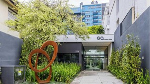 Un edificio moderno con entrada de vidrio, una gran escultura de metal y follaje.
