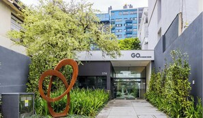 A modern building with a glass entrance, a large metal sculpture, and a sign reading 'GO OIDÁE BAIXA'. - GO Cidade Baixa by My Way (Porto Alegre)