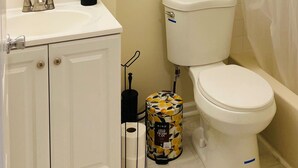 A bathroom with a toilet, sink, and a painting of a sunset. - Charming Retreat in the Heart of the City (Springfield)