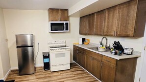 A compact kitchen with a refrigerator, microwave, stove, and wooden cabinets. - Charming Retreat in the Heart of the City (Springfield)