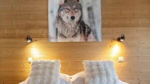 A bedroom with a wooden wall, two bedside lamps, and a framed picture of a wolf. - Petit Social - Chaleureux | 4pax | Vue Montagne | Remontée300m (Chamonix-Mont-Blanc)