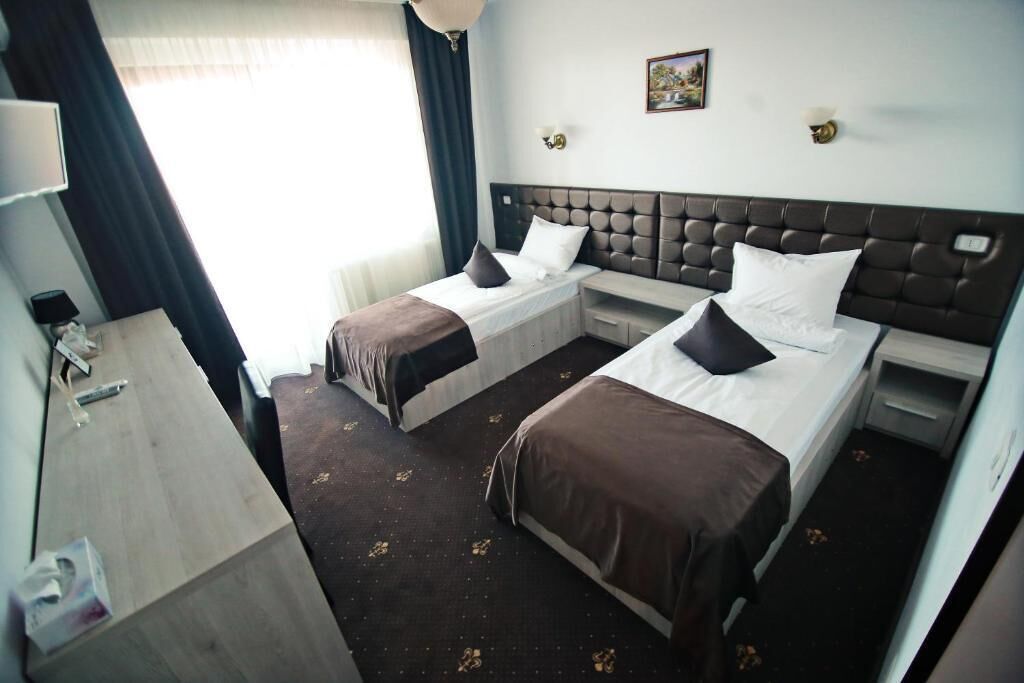 A hotel room with two single beds, a desk, and a chair.