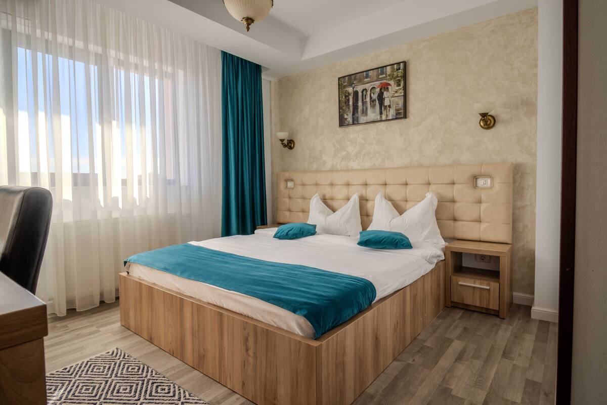 A neatly arranged bedroom with a large bed, a bedside table, and a chair.