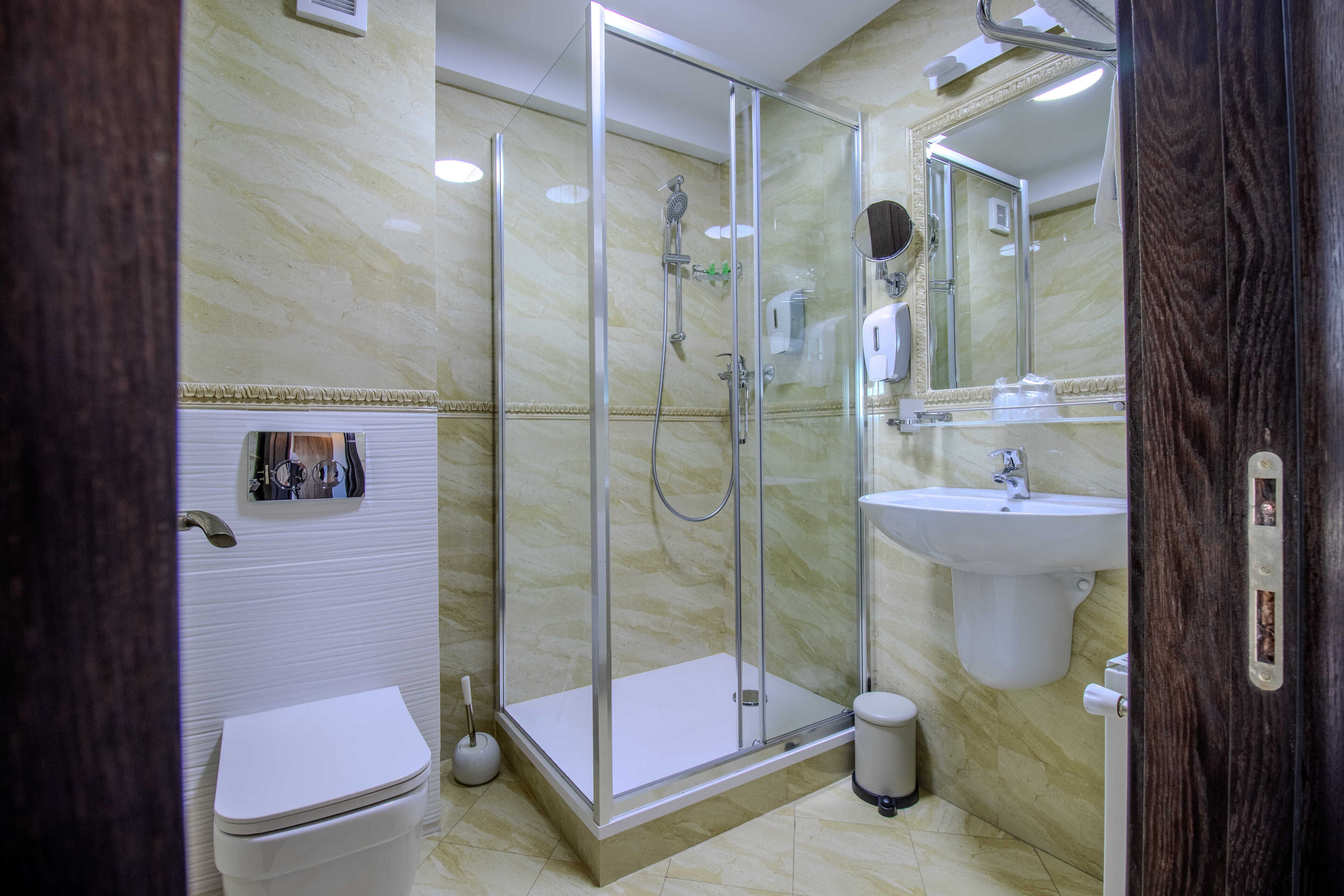 A modern bathroom with a glass-enclosed shower, a white sink, and a toilet.