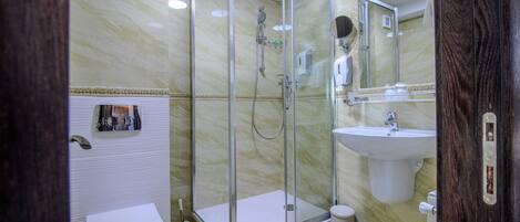 A modern bathroom with a glass-enclosed shower, a white sink, and a toilet.