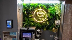 A coffee station with a neon sign, a digital coffee machine, and a menu board. - Casa Munteneasca Alessandro (Bradu)