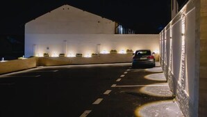 A nighttime view of a parking area with a car parked near a building with illuminated windows. - Casa Munteneasca Alessandro (Bradu)