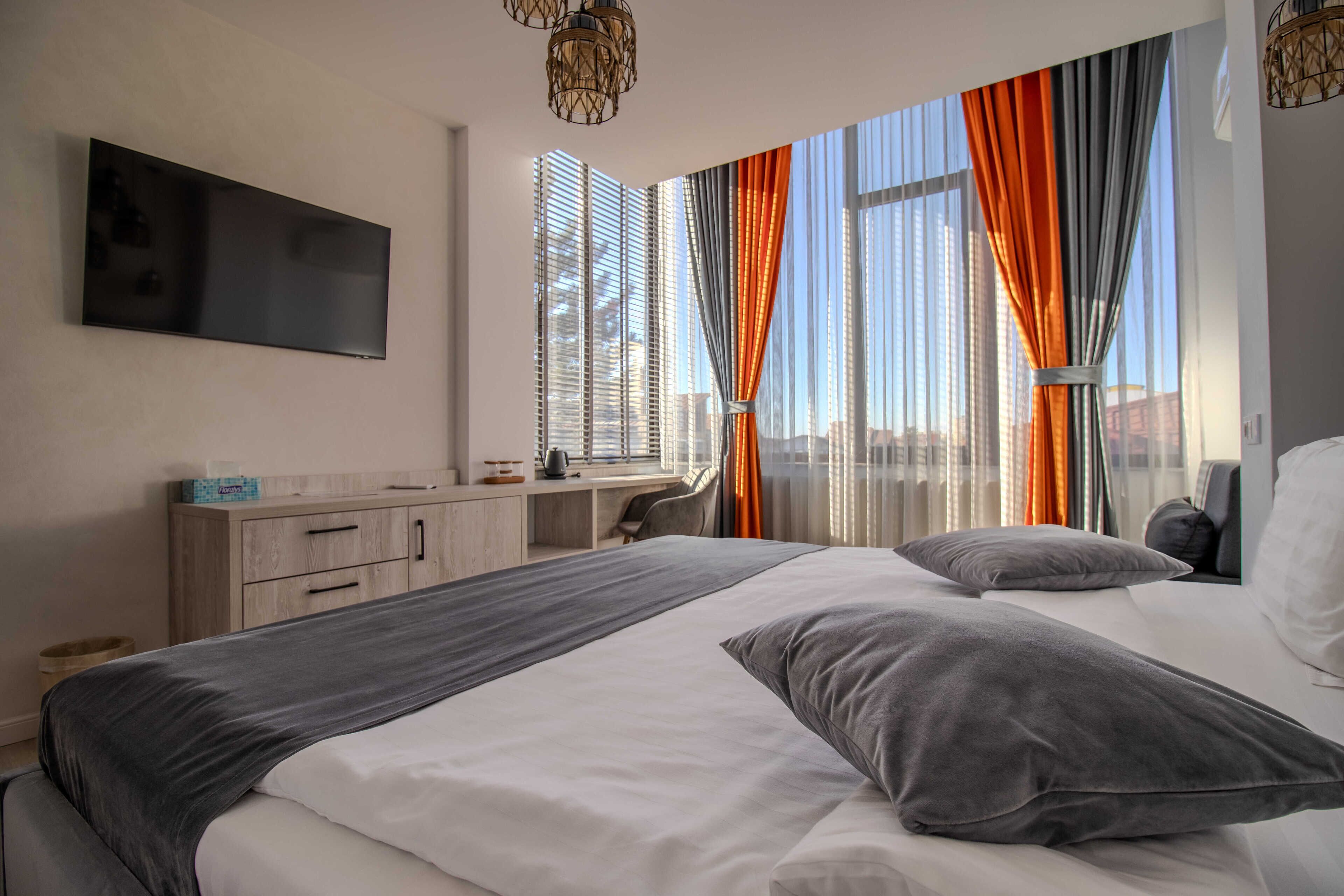 Une chambre d’hôtel moderne, dotée d’un grand lit, d’un bureau et d’une télévision.