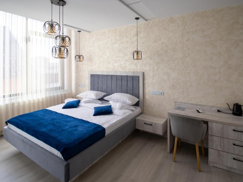 A modern bedroom with a bed, bedside table, desk, and chair.