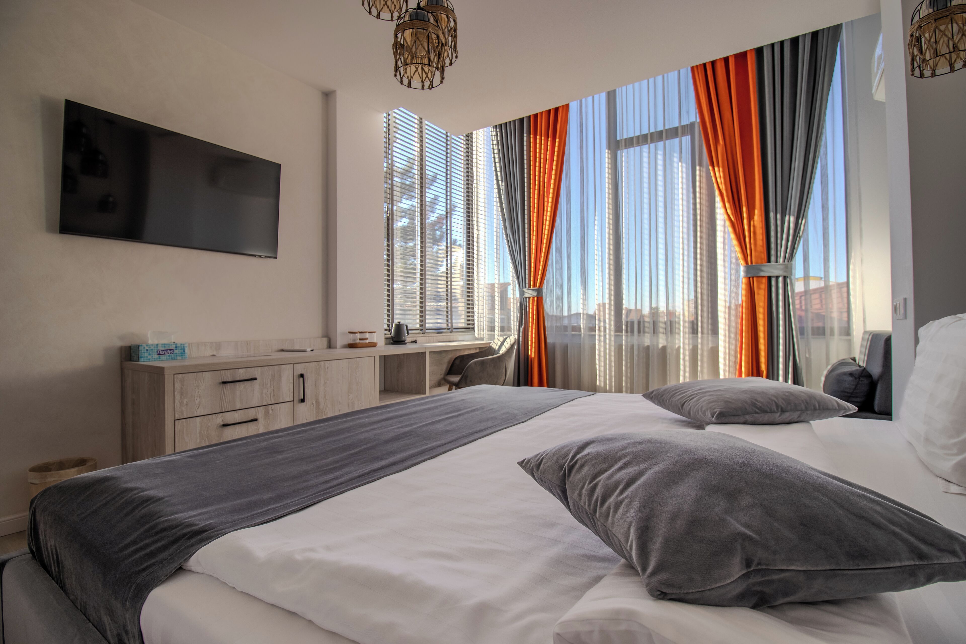 A modern hotel room with a large bed, a desk, and a TV mounted on the wall.
