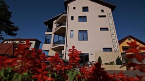 A multi-story hotel with balconies, a sign reading "Casa Miniera," and a clear blue sky. - Casa Munteneasca Alessandro (Bradu)