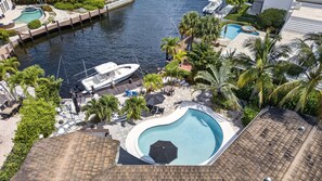 A swimming pool surrounded by palm trees and a dock with boats. - Minutes to Marlin! Sailor's Cove at Santa Barbara Shores...Now Available! (Pompano Beach)