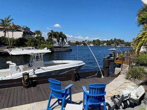A marina with a docked boat, two blue chairs, and a wooden deck. - Minutes to Marlin! Sailor's Cove at Santa Barbara Shores...Now Available! (Pompano Beach)