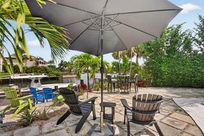 An outdoor patio with chairs, a table, and a large umbrella. - Minutes to Marlin! Sailor's Cove at Santa Barbara Shores...Now Available! (Pompano Beach)