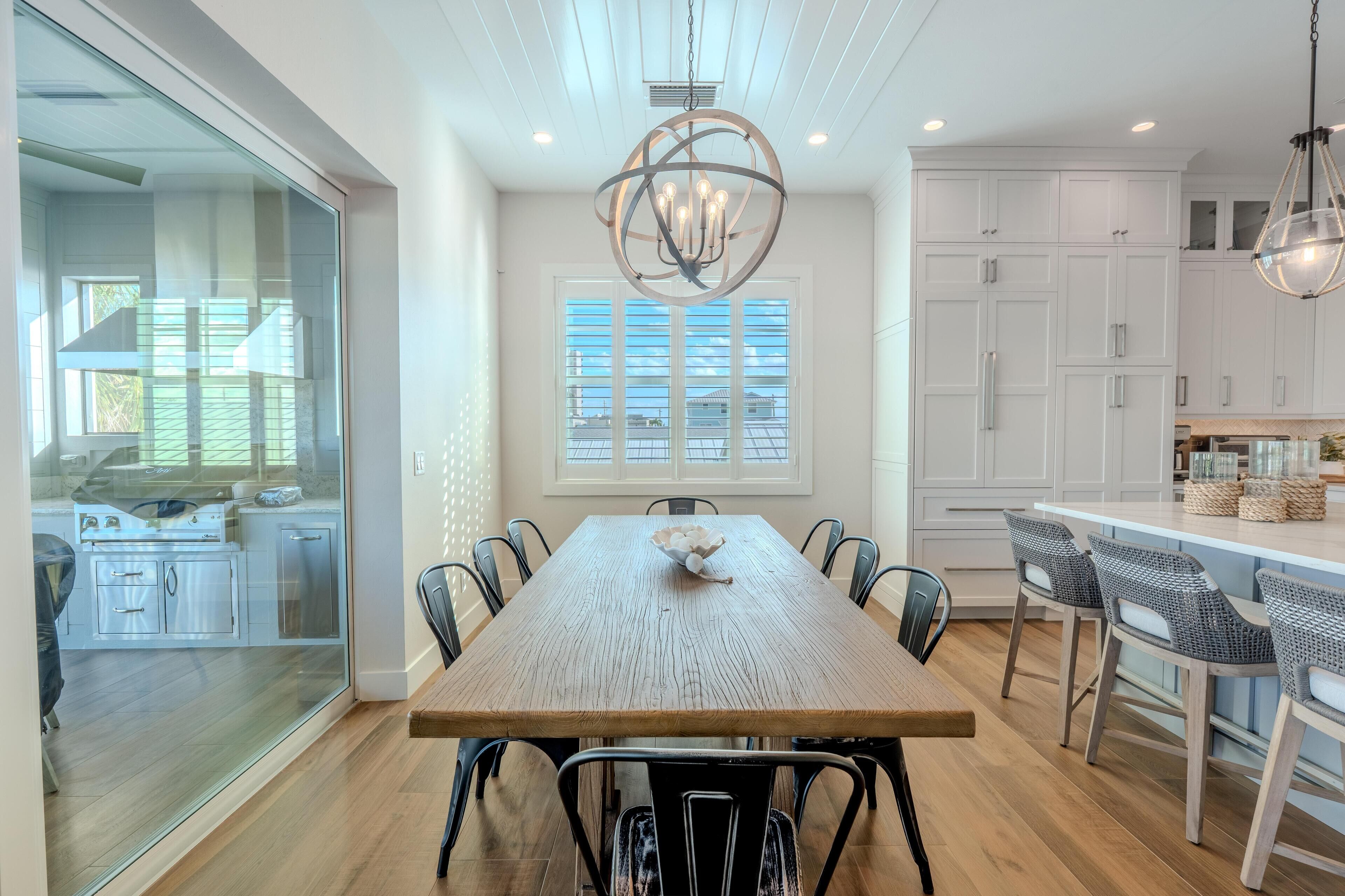 A modern kitchen with white cabinets, a wooden dining table, and black chairs.
