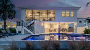 Une maison moderne à deux étages, dotée d’une piscine, d’un espace salon extérieur et d’un escalier menant à l’étage supérieur.