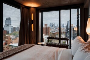 Een hotelkamer met een groot raam, een bed, een stoel en een klein tafeltje.
