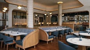 A restaurant with a modern interior, featuring wooden booths and tables, and a bar area with a variety of bottles. - The Merchant Hotel Lower East Side (New York)