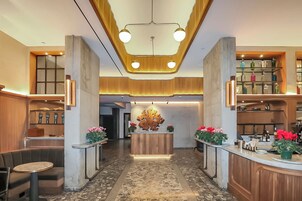 A hotel lobby with a central reception desk, seating areas, and a decorative ceiling.