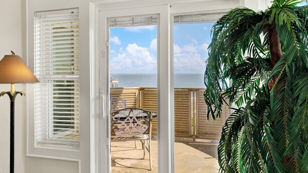 A room with a sliding glass door leading to a balcony with a view of the sea. - Superb 3-bedroom ocean view condo located within walking distance to everything! (Tybee Island)