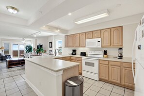A modern kitchen with white cabinets, a central island, and a stainless steel trash can. - Superb 3-bedroom ocean view condo located within walking distance to everything! (Tybee Island)