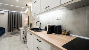 Et moderne køkken med hvide skabe, en træbordplade og en indbygget komfur.