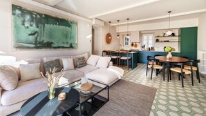 Un salon moderne comprenant un grand tableau, un canapé, une table basse et un coin repas avec une table et des chaises.