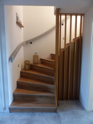 Eine Holztreppe mit geschwungener Handlauf, die zu einer Zwischenebene führt.
