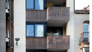 Un edificio a più piani con balconi, ampie finestre e un ingresso a livello strada con un negozio.