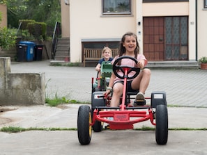 A child riding a small, red, wheeled vehicle outdoors. - Holiday Farm Henn “Panorama” with Pool, Animals and Playground (Weikersheim)