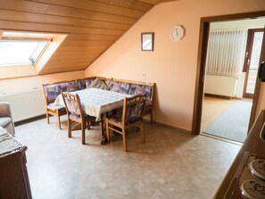 Un espace repas comprenant une table et des chaises, un plafond en bois, une horloge et une fenêtre.