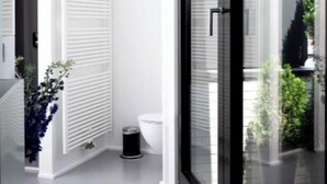 A modern bathroom with a glass door, white walls, and a small window. - Suite aux Anges N°3 (Duplex) (Antwerpen)