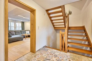 Una escalera con barandales de madera, un suelo estampado y un sofá en la habitación contigua.