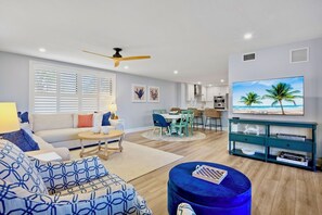 A modern living room with a sofa, ottoman, and a dining area with chairs and a table. - Gulf and Bay Club-B110- Just 5 minutes from Siesta Beaches! (Siesta Key)