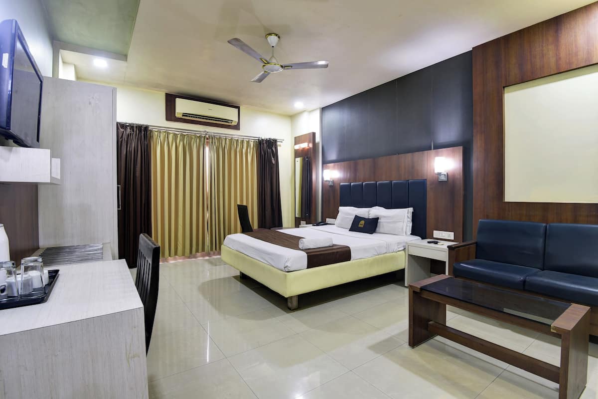 A hotel room with a bed, bedside table, desk, and a sofa.