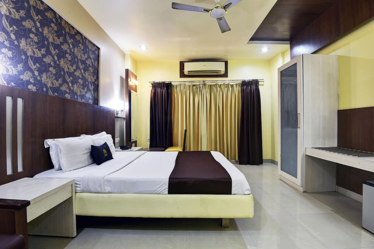 A hotel room with a bed, bedside table, wardrobe, and a ceiling fan.
