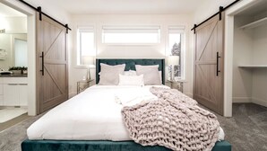 Ein Schlafzimmer mit einem Bett, einem großen Fenster und einem Kleiderschrank mit Schiebetüren.