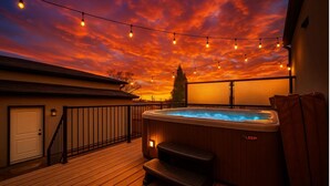 Ein Whirlpool auf einer Holzterrasse mit Sonnenuntergangsblick, Lichterketten und dem LEAP-Logo.
