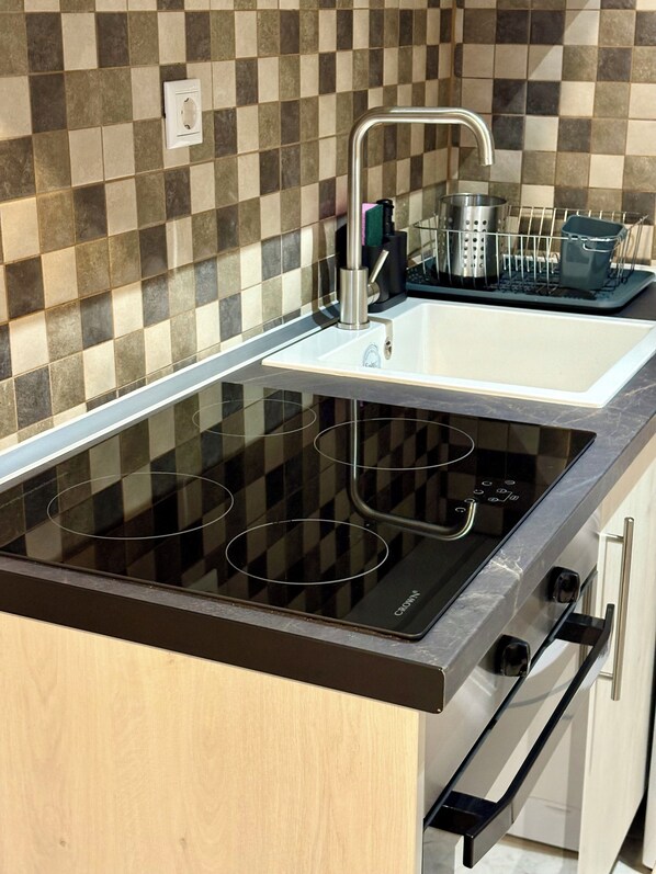 A modern kitchen with a black induction cooktop, a stainless steel sink, and a dish rack. - Domus Philippou Tsimiski II, center of Thessaloniki (Thessaloniki)