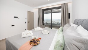 Une chambre d’hôtel moderne avec un grand lit, une vue sur la mer et un balcon.