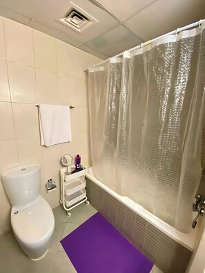 Une salle de bain équipée de toilettes, d’une baignoire et d’un rideau de douche.