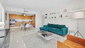 En moderne stue med en turkis sofa, et glasbord og en gulvlampe.
