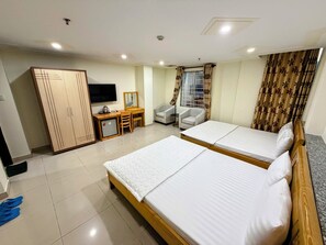 A hotel room with two beds, a desk with a chair, a wardrobe, a television, and a window with curtains. - Khach San Hoang Tay (Hoa Hung)