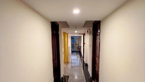 A hotel hallway with a polished marble floor, wooden doors, and a ceiling light.