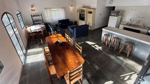 A spacious living area with a wooden dining table, blue sofas, and a kitchen area with a tiled backsplash. - Rancho dos Capelos (Nazaré Paulista)