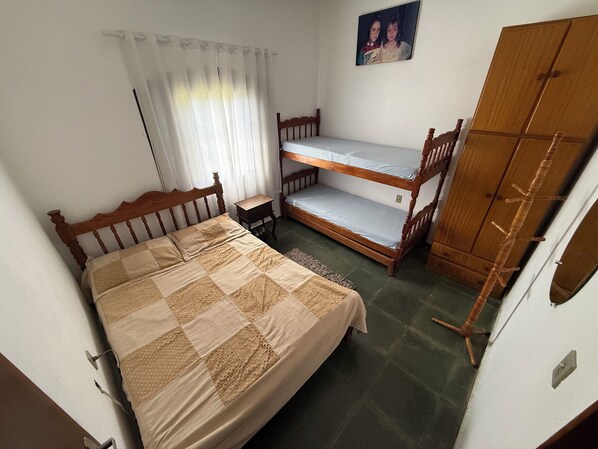 A bedroom with a single bed, a bunk bed, a wooden wardrobe, and a small table. - Rancho dos Capelos (Nazaré Paulista)